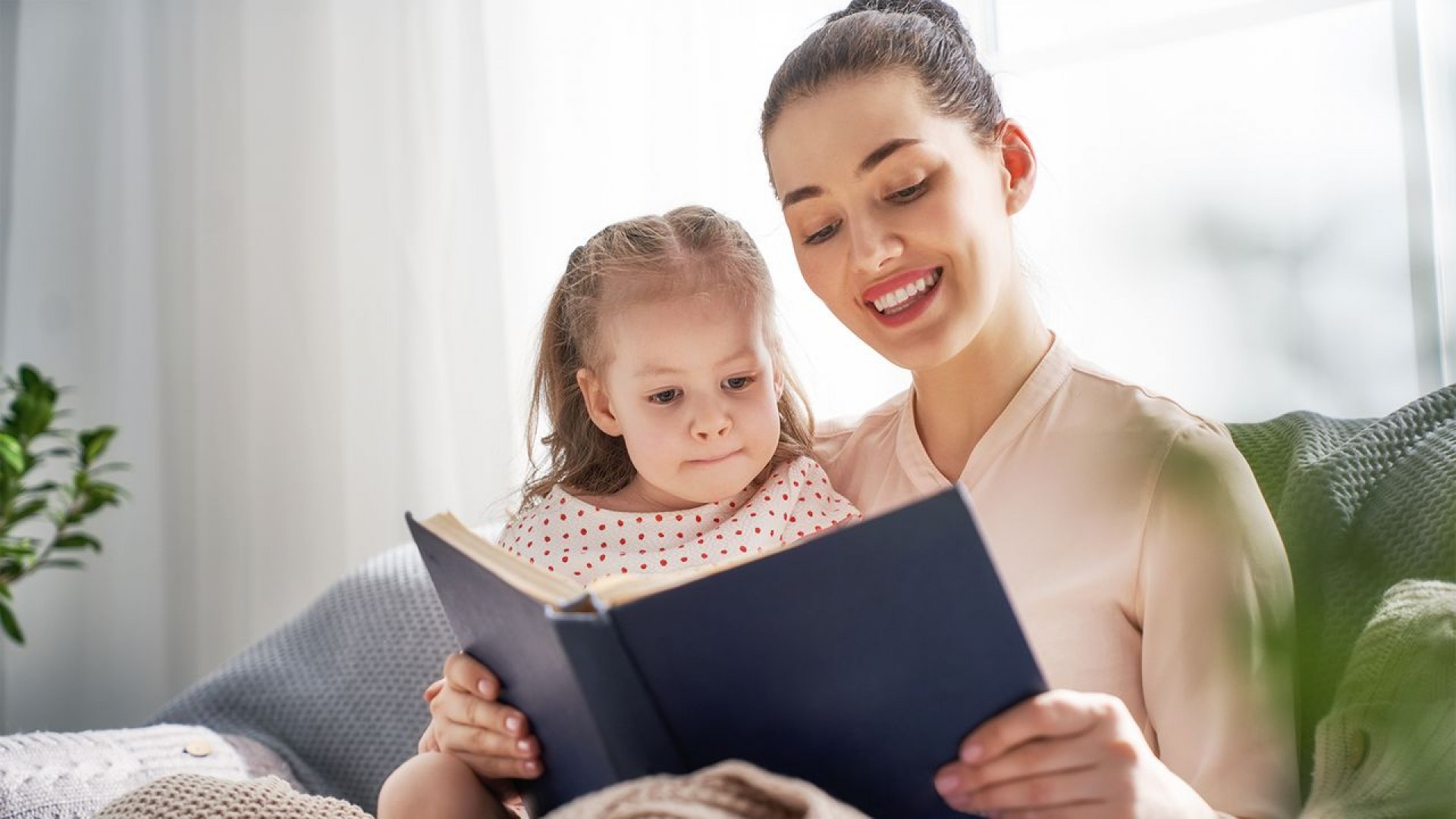 Красивая мама читает книгу с ребенком